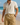 A smiling man in a cream short-sleeve shirt and khaki linen-blend cargo shorts walking on a sunny beach in Australia, hands in pockets, with waves in the background