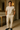 Australian male model in his 30s wearing beige drawstring linen-blend pants and navy moccasins, standing in a luxurious, well-lit interior with a gold-accented console and neutral decor