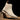 Beige Chelsea boot on a wooden block with a dark background