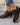 Black ankle boots with brown soles worn by a person on a light gray floor