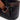 Black textured bag with brown strap and gold buckle on a white background