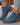 Blue ankle boots with brown soles worn with light blue jeans on a neutral background