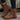 Brown suede boots with buckles worn by a person on a wooden surface