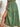 Green pleated skirt with a slit worn by a person on a light background