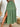 Green tiered skirt with a slit worn by a person, against a white wall