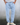 Man wearing light blue textured drawstring pants with relaxed fit and hands in pockets, paired with white sneakers with background