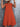 Orange tiered dress worn by a person against a gray textured wall