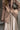 Person wearing a beige coat and holding a patterned handbag