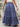 Person wearing a blue floral tiered skirt on a stone staircase