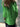Person wearing a bright green jacket standing against a stone wall
