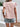 Person wearing a floral top and denim shorts against a white wall