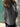 Person wearing a gray jacket standing against a stone wall