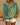 Person wearing a green and yellow patterned top with white shorts on a beige background
