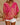 Person wearing a vibrant pink and red patterned top with white shorts against a neutral background