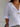 Person wearing a white shirt with rolled-up sleeves and layered necklaces against a neutral background