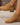 Tan ankle boots worn by a person on a neutral background