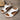 White wedge sandals with brown soles on a wooden surface
