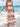 Woman in a long, patterned dress standing on a beach with ocean in the background