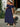 Woman in a navy blue off-shoulder dress holding a floral bouquet outdoors