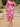 Woman in a pink floral dress standing on stone steps outdoors