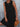 Woman wearing a black dress holding a wooden clutch against a gray background