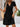 Woman wearing a black dress with a wooden wall and plant in the background