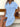 Woman wearing a blue button-up dress sitting on a wooden bench