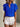 Woman wearing a blue ruffled blouse and white shorts against a neutral background