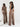 Woman wearing a brown jumpsuit standing in front of a white curtain
