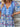 Woman wearing a colorful blue patterned dress with a wooden background, close up