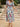 Woman wearing a colorful floral dress standing on stone steps outdoors