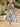 Woman wearing a colorful floral dress standing on steps outdoors