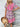 Woman wearing a colorful patterned dress with a straw hat against a wooden background