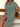 Woman wearing a green button-up dress sitting on a wooden bench