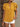 Woman wearing a mustard yellow blouse with ruffled sleeves against a neutral background