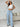Woman wearing a white crop top and blue striped pants in a living room