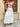 Woman wearing a white lace dress standing in front of a stone wall