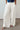 A woman wearing white wide-leg pants
