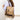 Beige backpack with brown accents worn by a person on a white background