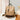 Beige textured backpack with brown accents on a lace tablecloth