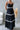 Black dress with white trim worn by a person in a minimalistic room