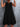 Black sleeveless dress worn by a person against a gray textured wall