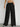 Black wide-leg pants worn by a women on a plain bacground