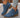 Blue ankle boots with brown soles worn with light blue jeans on a neutral background