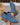 Blue suede ankle boots with brown soles held by a hand on a neutral background