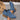 Blue suede ankle boots with brown soles held by a hand on a neutral background