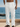 Breathable white linen-blend pants for men with drawstring waist and button details. Ocean view. 