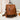 Brown textured backpack on a lace surface with a neutral background