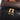 Close-up of a black textured bag with gold zippers and brown woven top