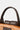 Close-up of a brown leather handbag handle on a light gray background